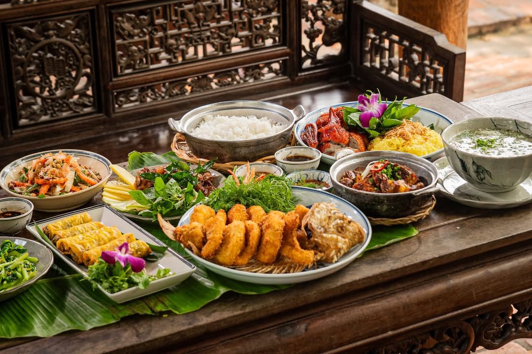 Mâm cơm Việt nhiều món bày trên sập gỗ chạm khắc tại Nhà hàng Bến Bạc Mâm cơm Việt nhiều món bày trên sập gỗ chạm khắc tại Nhà hàng Bến Bạc