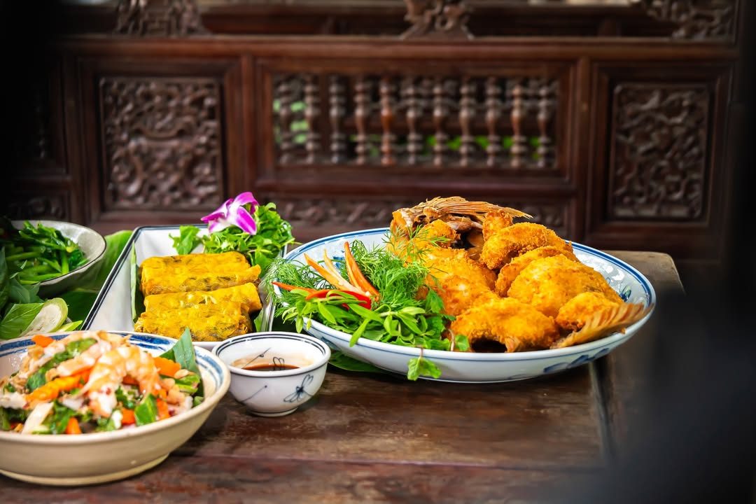 Cá chiên giòn, chả trứng và nộm rau bày trên bàn gỗ tại Nhà hàng Bến Bạc Cá chiên giòn, chả trứng và nộm rau bày trên bàn gỗ tại Nhà hàng Bến Bạc